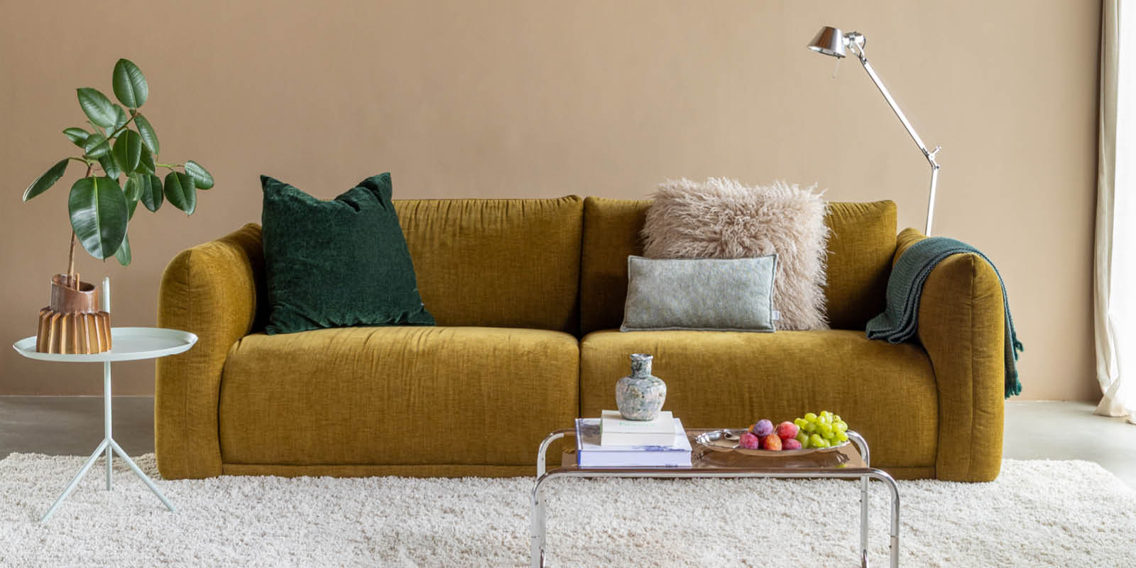 Okergele bank Lova van By SIDDE met groene en roze kussens in een woonkamer gestyld door Sanne Jutte