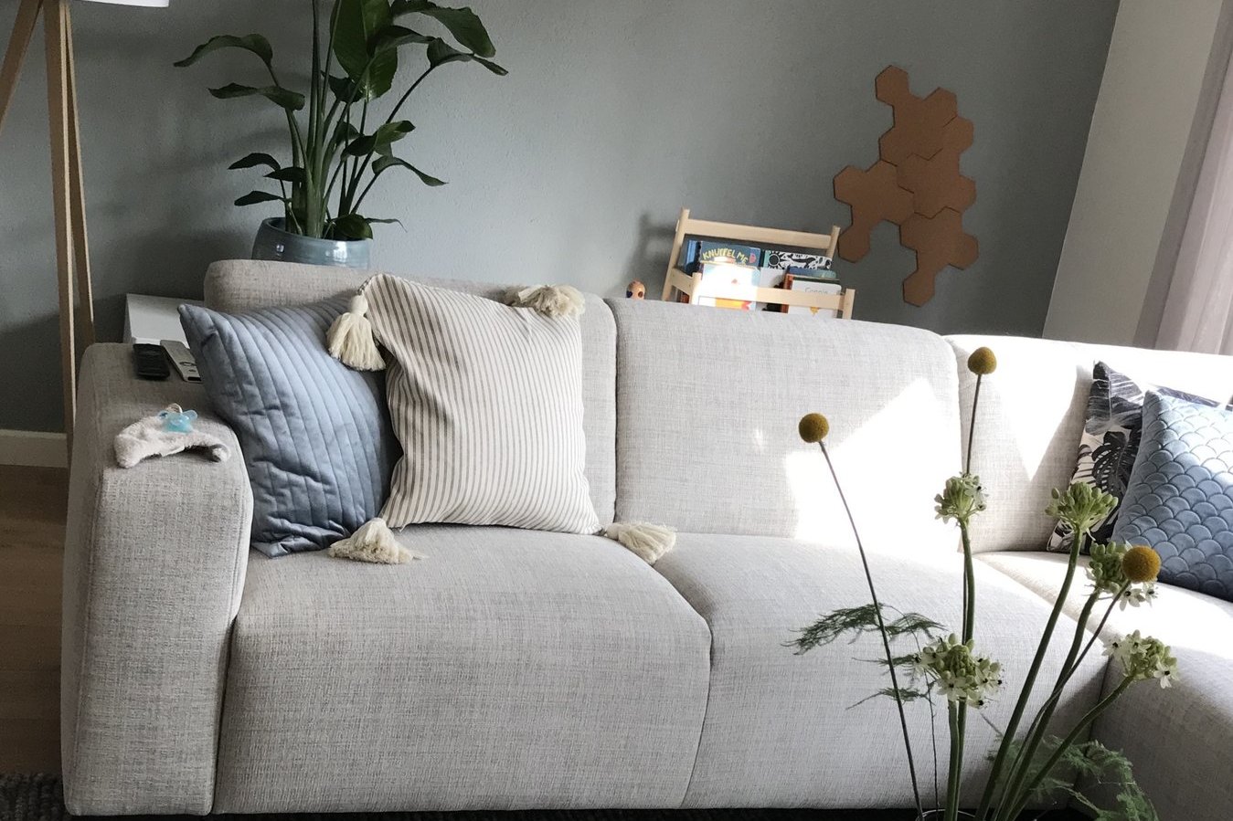Lichte woonkamer met beige hoekbank, kussens en groen in een familiehuis