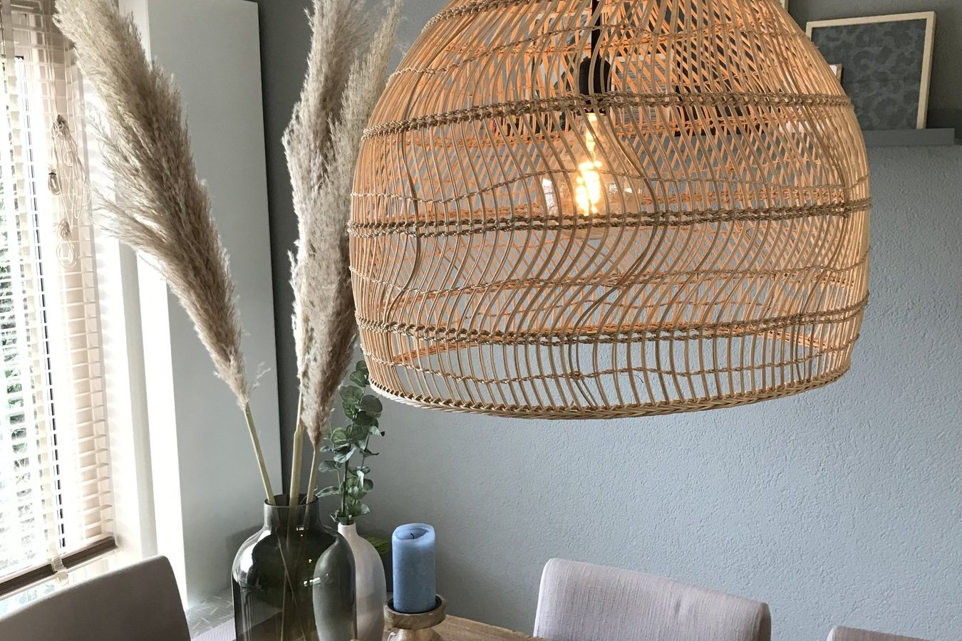 Eethoek met rotan hanglamp en droogbloemen bij het raam
